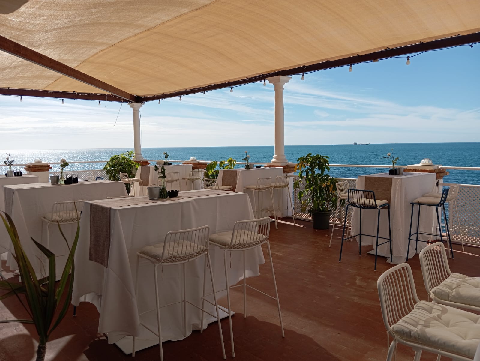 Mesas altas bajo la pérgola del Lounge Terrace con el mar de fondo